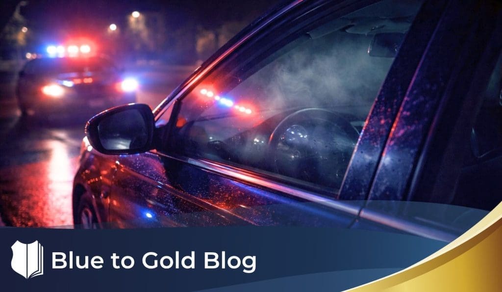 Nighttime traffic stop with police lights reflecting on a sedan and faint haze visible inside the driver’s window.